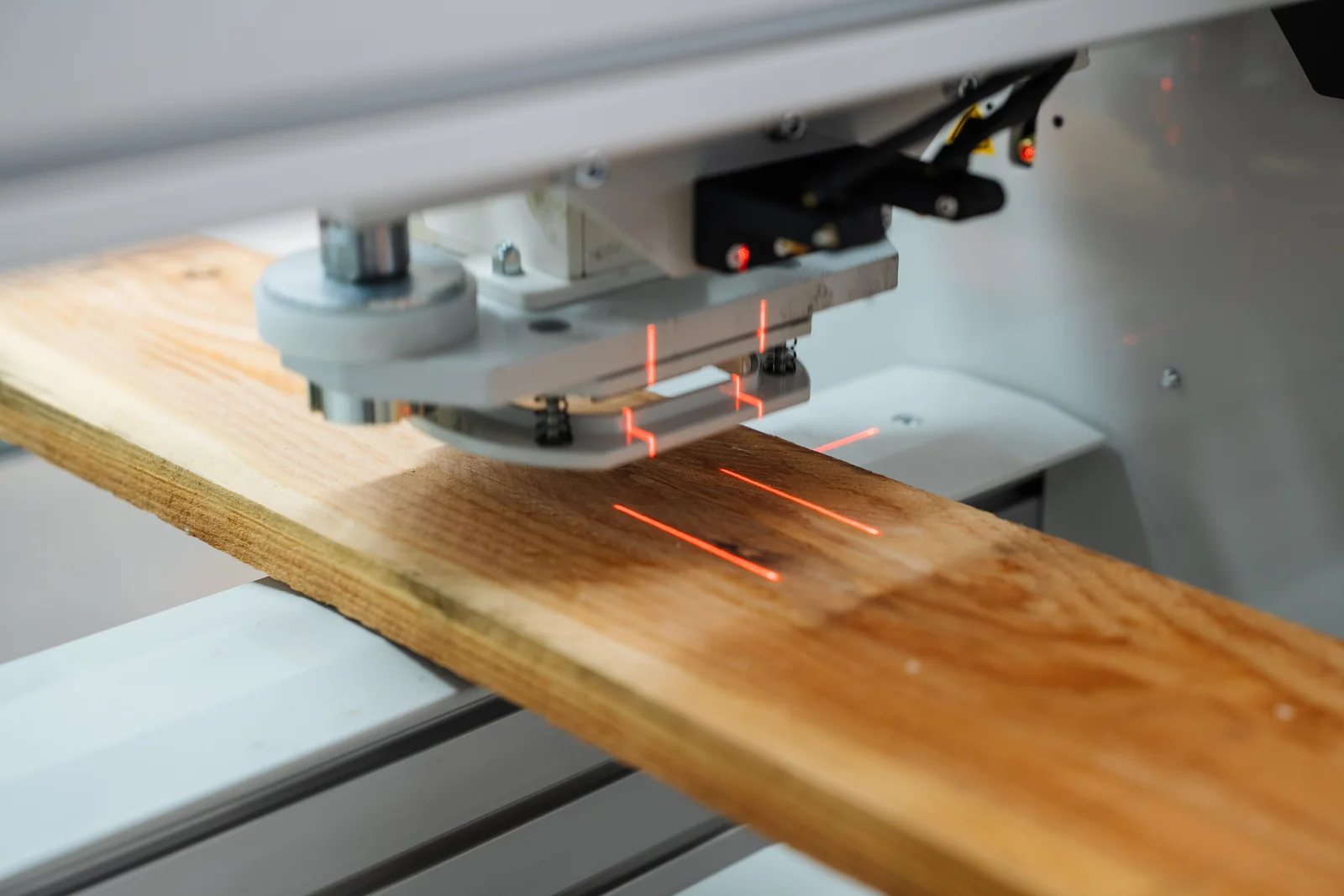 Rote Laserlinien eines AELA-Prüfkopfs auf der Oberfläche eines Holzbretts